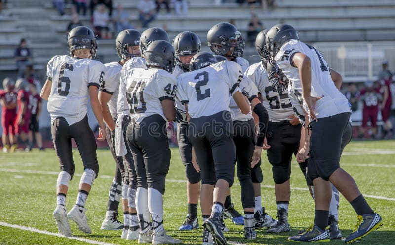 Huddling dei giocatori di football americano della High School immagini stock Huddling dei giocatori di football americano della High School immagini stock
