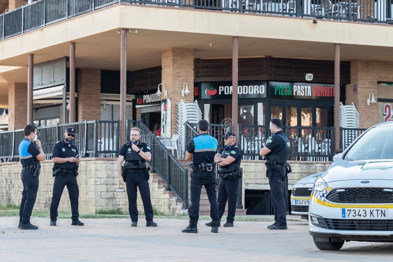 Huelva, Spain - July 4, 2020: Spanish police with `Local Police` logo emblem on uniform maintain public order in the Islantilla beach promenade. Huelva, Spain - July 4, 2020: Spanish police with `Local Police` logo emblem on uniform maintain public order in the Islantilla beach promenade