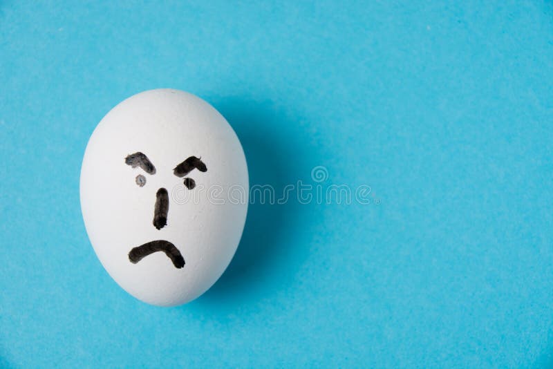 Huevo con una cara enojada y descontenta. aislar sobre un fondo azul
