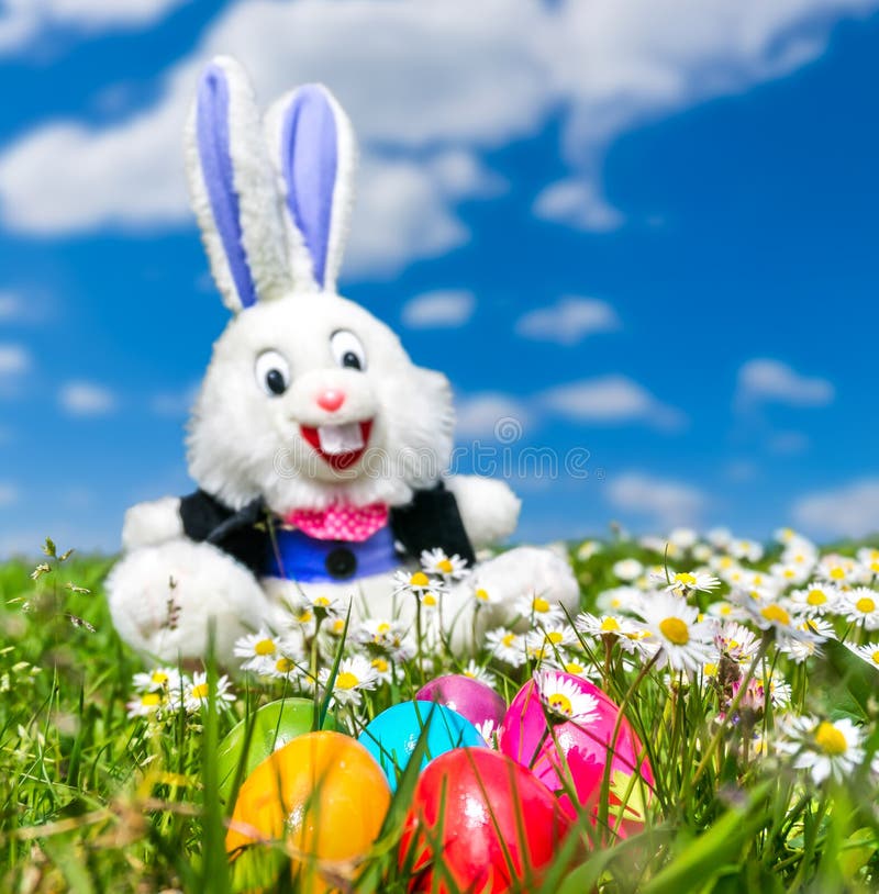 Huevos de Pascua coloridos con el conejito de pascua divertido que miente en hierba foto de archivo libre de regalías Huevos de Pascua coloridos con el conejito de pascua divertido que miente en hierba foto de archivo libre de regalías