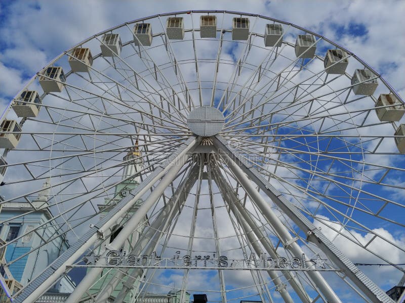 Huge Ferris wheel at city center. entertainment for adults and children. blue sky with clouds on background. low angle image stock photo Huge Ferris wheel at city center. entertainment for adults and children. blue sky with clouds on background. low angle image stock photo