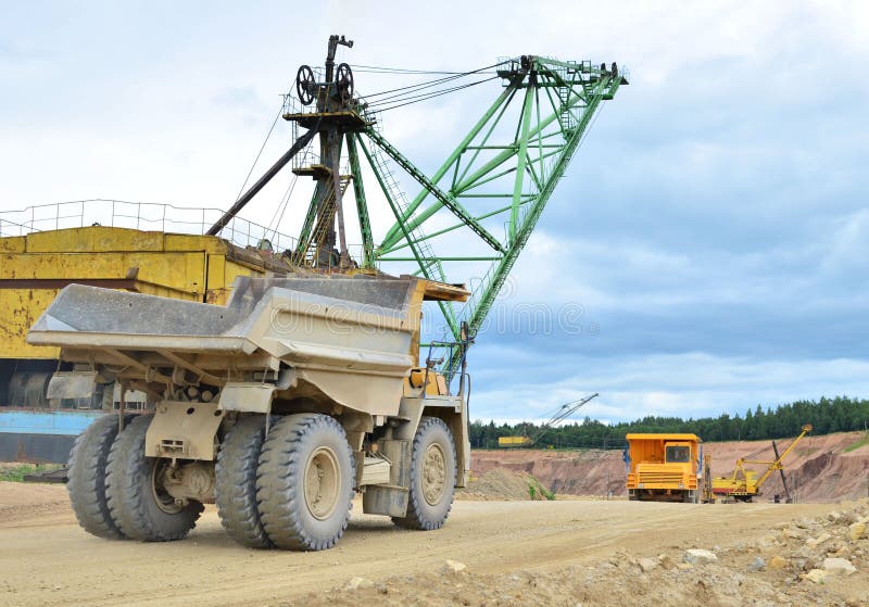 Huge mining excavator and dump trucks work in an open pit. royalty free stock photos