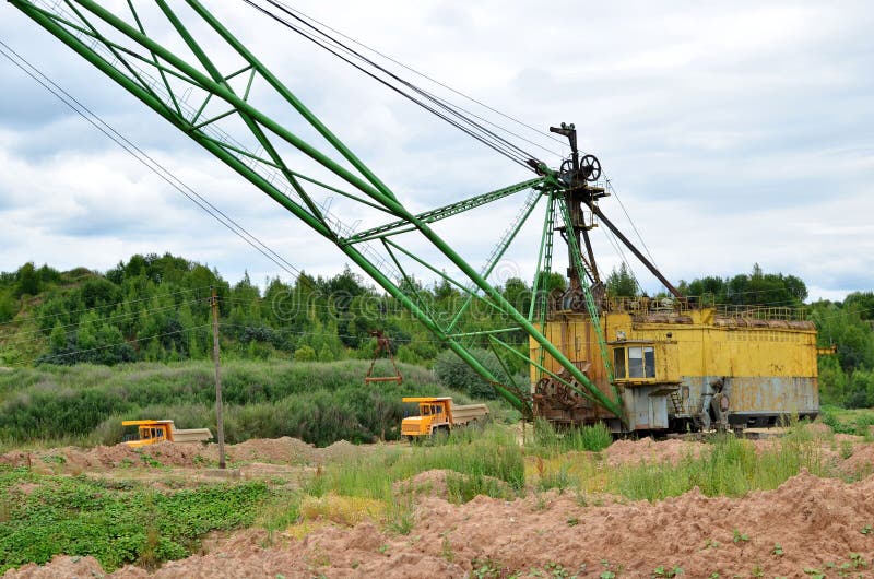 Huge mining excavator and dump trucks work in an open pit. stock photos