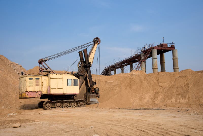 Huge mining excavator in the sand open-pit. Biggest digger working in quarry. Largest tracked machine with electric shovel. Heavy royalty free stock images