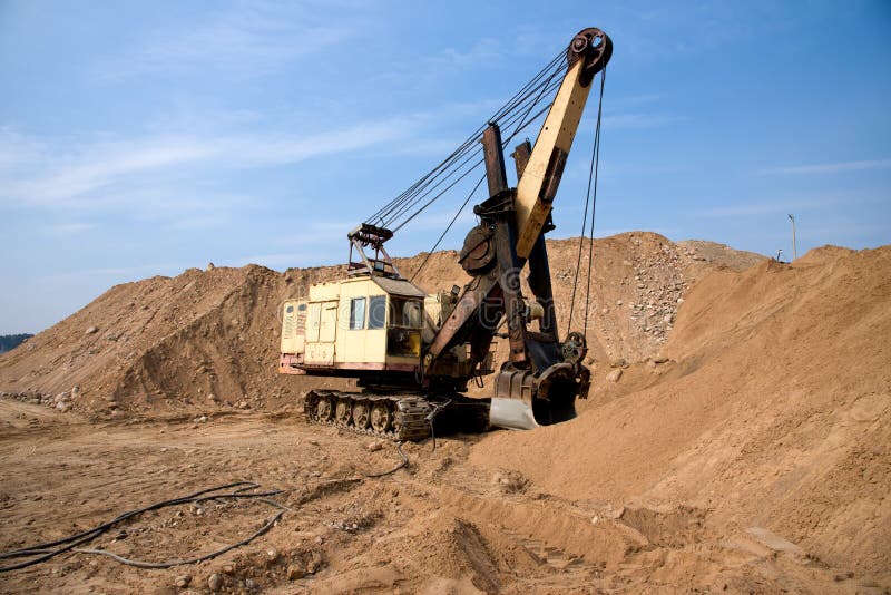 Huge mining excavator in the sand open-pit. Biggest digger working in quarry. Largest tracked machine with electric shovel. Heavy royalty free stock photos