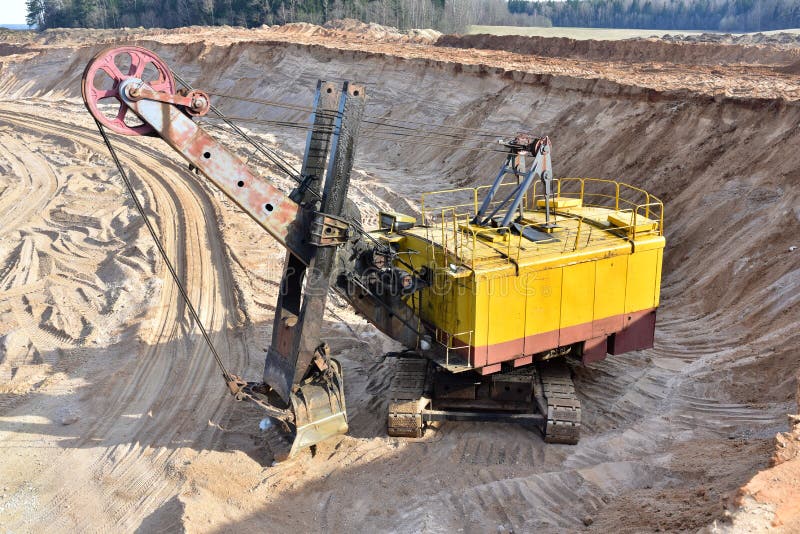 Huge mining excavator in the sand open-pit. Biggest digger working in quarry. Largest tracked machine with electric shovel. Heavy stock photography