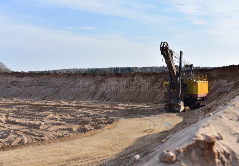 Huge mining excavator in the sand open-pit. Biggest digger working in quarry. Largest tracked machine with electric shovel. Heavy royalty free stock image