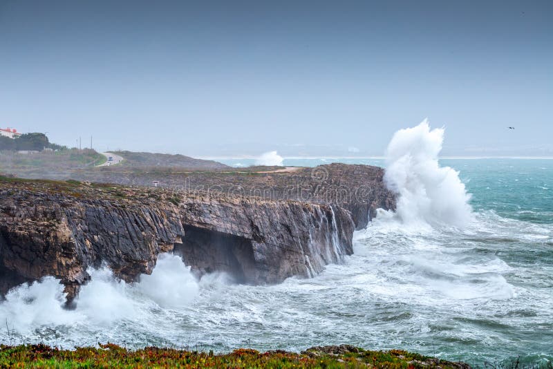 A huge ocean waves breaking on the coastal cliffs in at the cloudy stormy day. Breathtaking romantic seascape of ocean coastline.