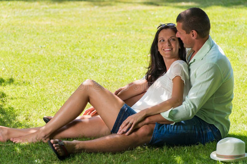 Hugging couple sitting in grass outdoors royalty free stock photos Hugging couple sitting in grass outdoors royalty free stock photos