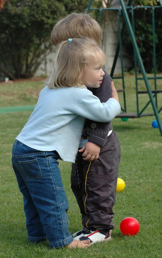 Caucásico pequeno lindo expresión en ella abrazó su el mejor un amigo posesión él su blanco mano sobre el bienvenido un nino sobre el después verano día festivo sobre el patio de juegos en patio trasero de jardín de infancia.