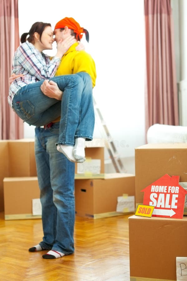 Home for sale sign with sold sticker and guy holding girlfriend in background. Home for sale sign with sold sticker and guy holding girlfriend in background