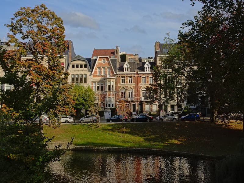 Huizen in eclectische Jugendstilstijl en bomen op de dijk van Ixelles-meren en kerk sainte-Croix royalty-vrije stock foto's Huizen in eclectische Jugendstilstijl en bomen op de dijk van Ixelles-meren en kerk sainte-Croix royalty-vrije stock foto's
