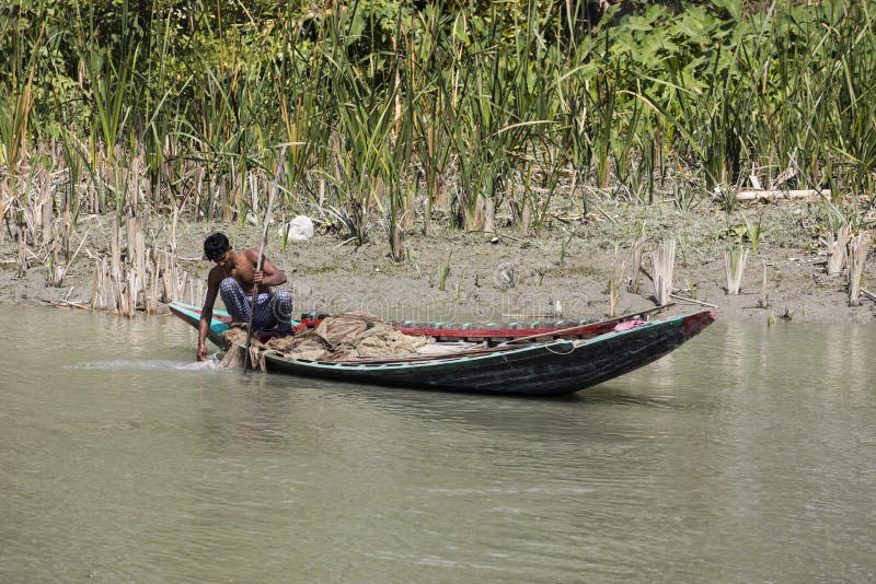 Hularhat, Bangladesh, el 27 de febrero de 2017: El pescador comprueba su red de pesca para saber si hay una captura acertada en s fotografía de archivo Hularhat, Bangladesh, el 27 de febrero de 2017: El pescador comprueba su red de pesca para saber si hay una captura acertada en s fotografía de archivo