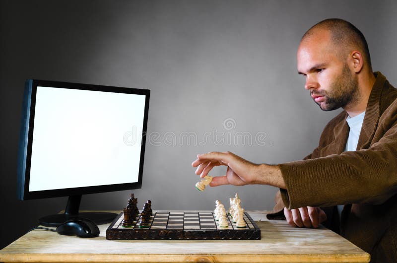 Man playing chess against computer Stock Photo