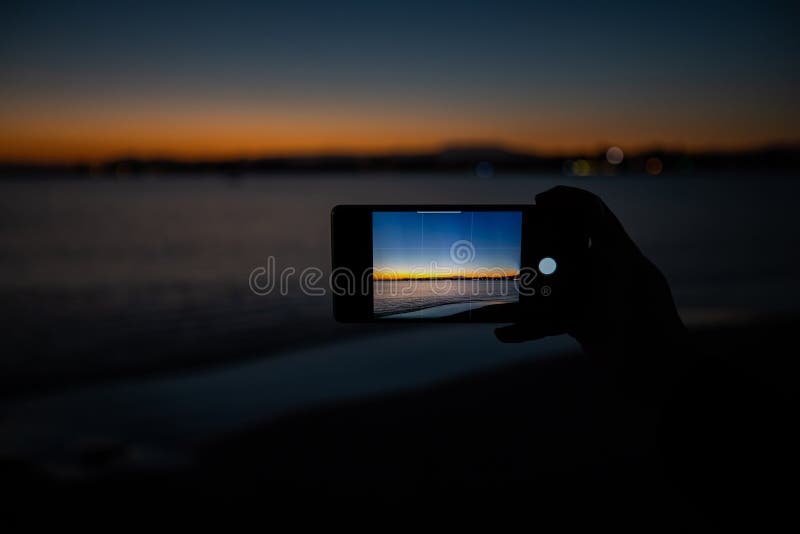 human hand holding a phone taking a picture of a sunset royalty free stock image human hand holding a phone taking a picture of a sunset royalty free stock image