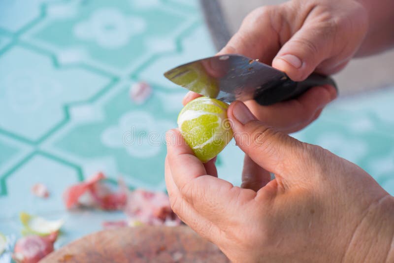 Human hands cut lemon peels with a knife