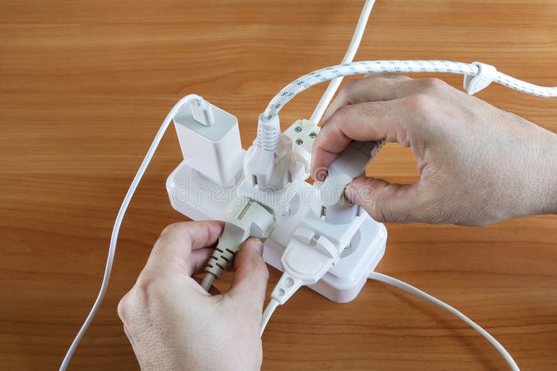 Human Hands Hold Plug Multiple Plugs On Table Electrical Outlet Is human-hands-hold-plug-multiple-plugs-on-table-electrical-outlet-is