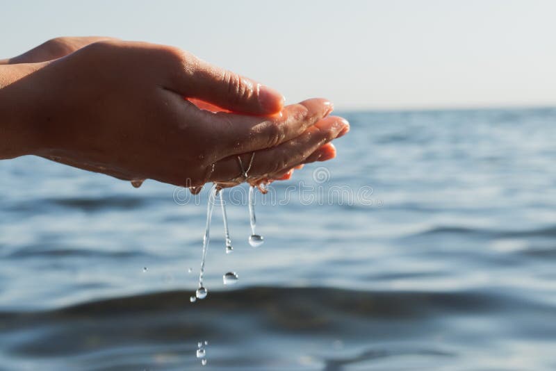 Human hands splashing pure water from sea.