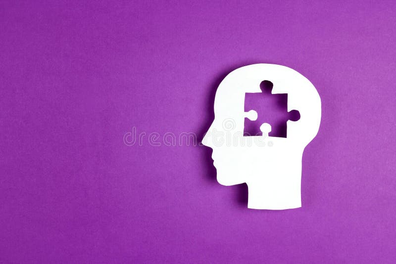 Human head paper silhouette with a puzzle piece cut out on the purple background. Mental health symbol