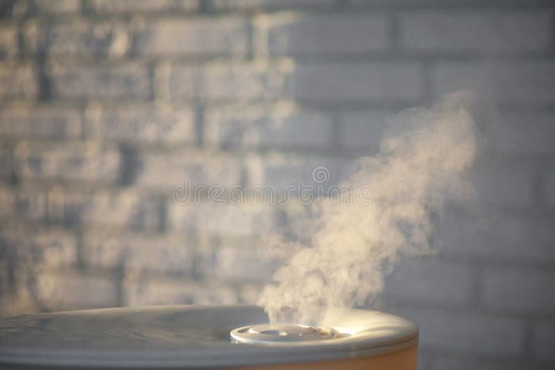 Humidifier spreading steam in the evening with white brick wall background royalty free stock photography