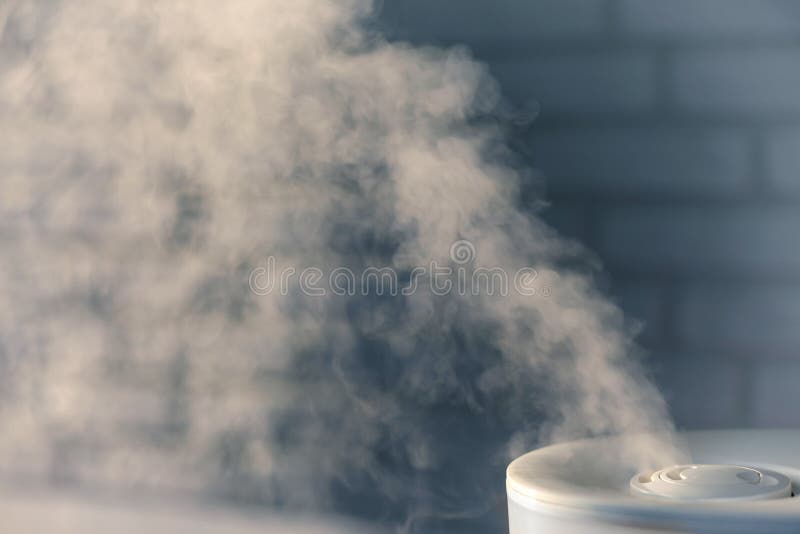 Humidifier spreading steam with white brick wall background stock images