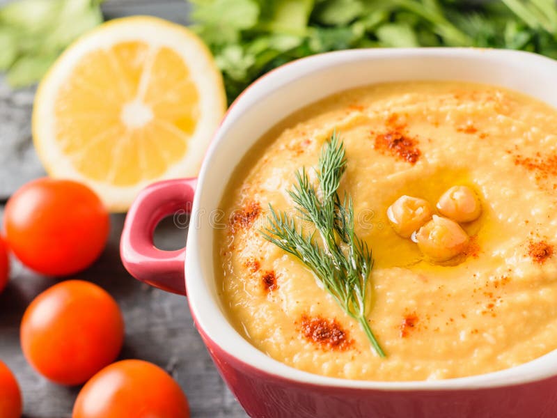 Hummus appena fatto in una ciotola ed in un limone porpora su una tavola con un pezzo di pane immagine stock libera da diritti
