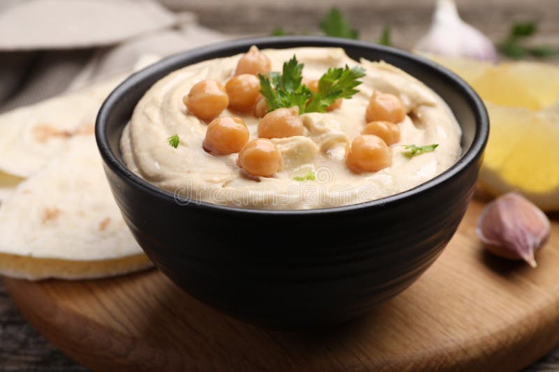 Hummus mit Kichererbsen und Pitas auf Holztisch serviert lizenzfreie stockfotografie