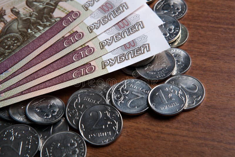 Russia`s hundred-ruble banknotes and coins on the table closeup. Russia`s hundred-ruble banknotes and coins on the table closeup