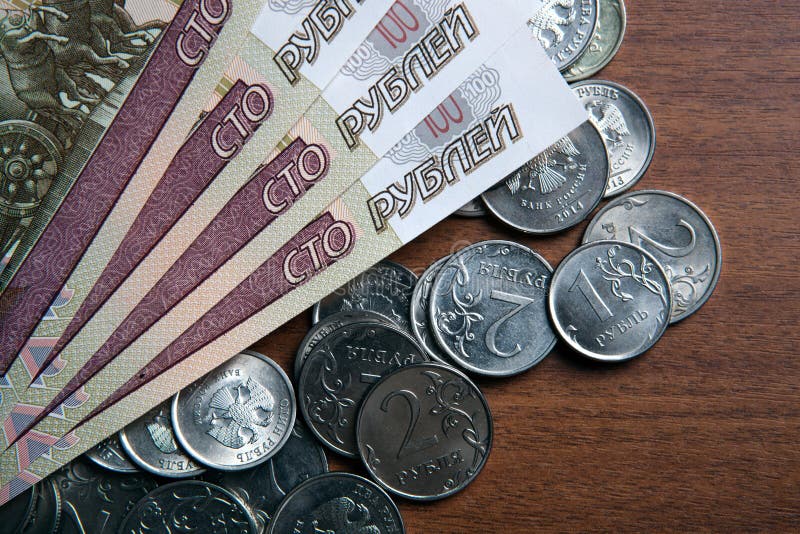 Russia`s hundred-ruble banknotes and coins on the table closeup. Russia`s hundred-ruble banknotes and coins on the table closeup