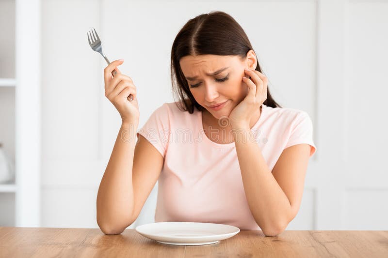 Hungrig Mädchen, das zu Hause leere Gruppe Tabelle betrachtet stockbild