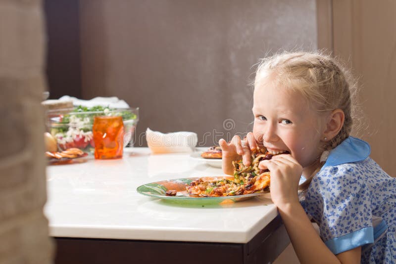 Hungrig nätt liten flicka som slukar hemlagad pizza arkivfoto Hungrig nätt liten flicka som slukar hemlagad pizza arkivfoto
