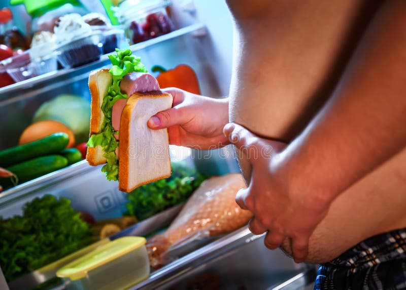 Hungriger Mann, der ein Sandwich in seinen Händen und in Stellung nahe bei hält lizenzfreies stockfoto Hungriger Mann, der ein Sandwich in seinen Händen und in Stellung nahe bei hält lizenzfreies stockfoto