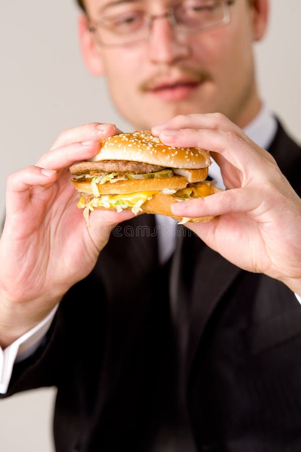 Hungry businessman eating hamburger