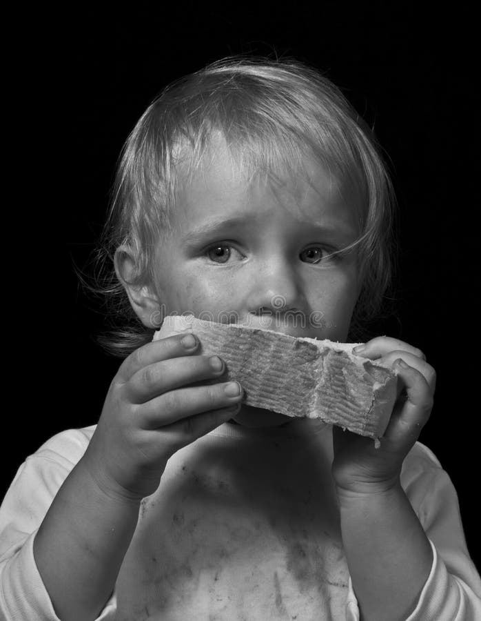 Poor hungry child eating bread