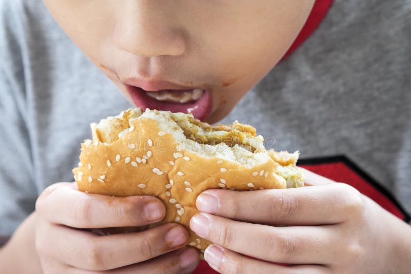 Close-up of a young kid eating chicken burger. Shallow depth of field. Close-up of a young kid eating chicken burger. Shallow depth of field.