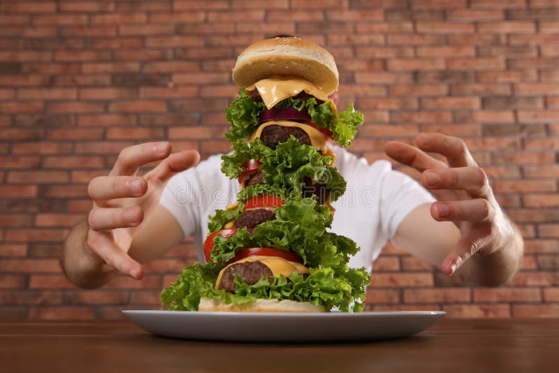 Hungry man with huge burger at wooden table