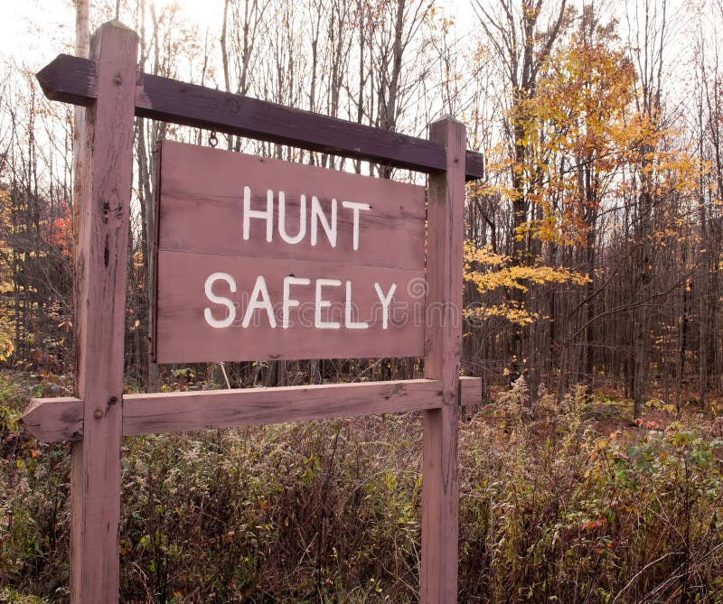 A `HUNT SAFELY` sign on in the fall woods