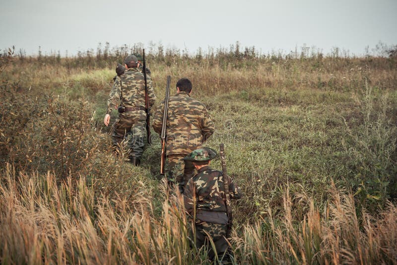 Hunters going up through rural field during hunting season stock image Hunters going up through rural field during hunting season stock image