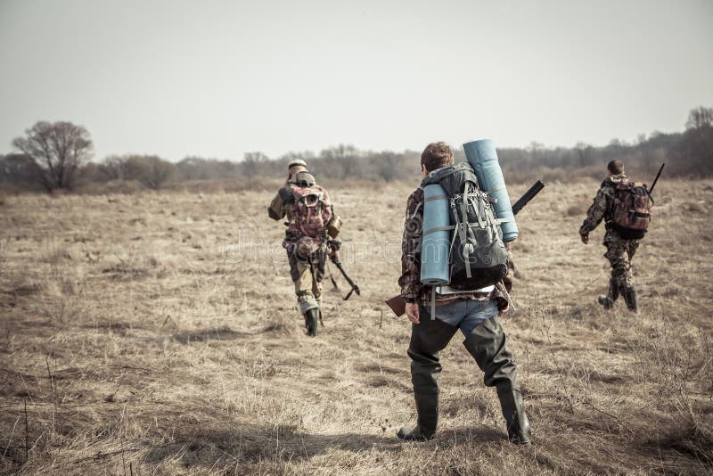 Hunting scene with group of hunters with backpacks and hunting ammunition going through rural field during hunting season in overc royalty free stock photo Hunting scene with group of hunters with backpacks and hunting ammunition going through rural field during hunting season in overc royalty free stock photo