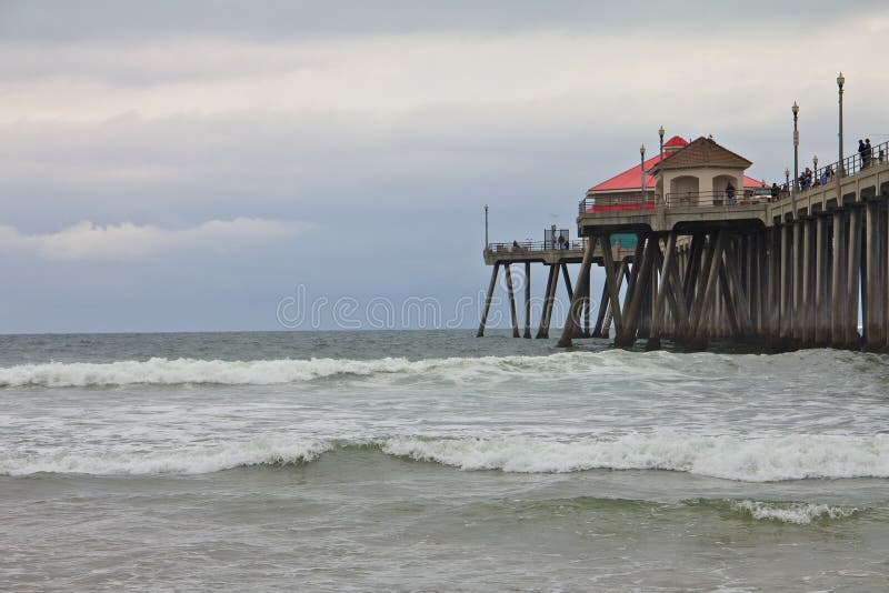 Huntington Beach Pier on a gloomy day with waves crashing. Red pylons stock images, royalty-free photos and pictures