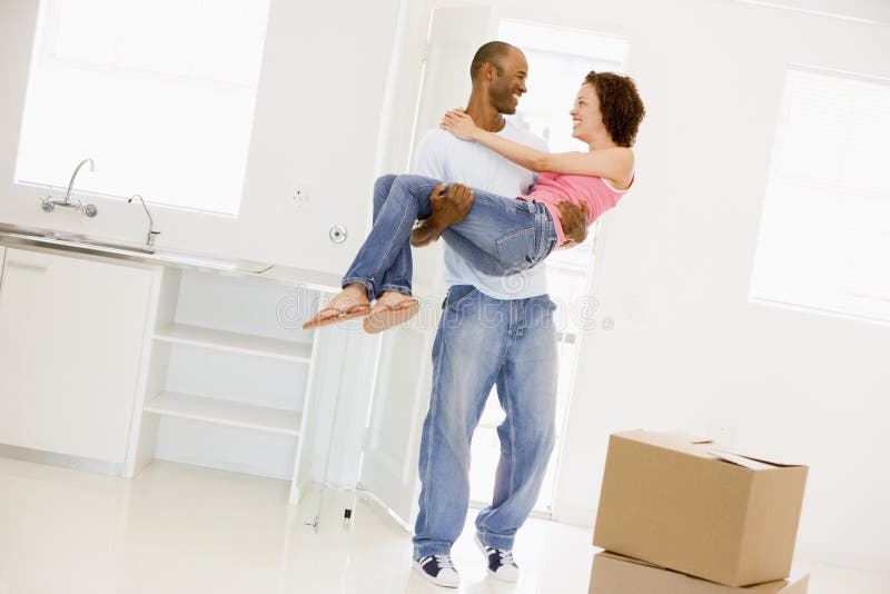 Husband holding wife in new home smiling