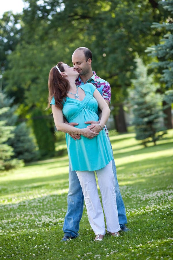 Husband with pregnant wife is resting in nature.