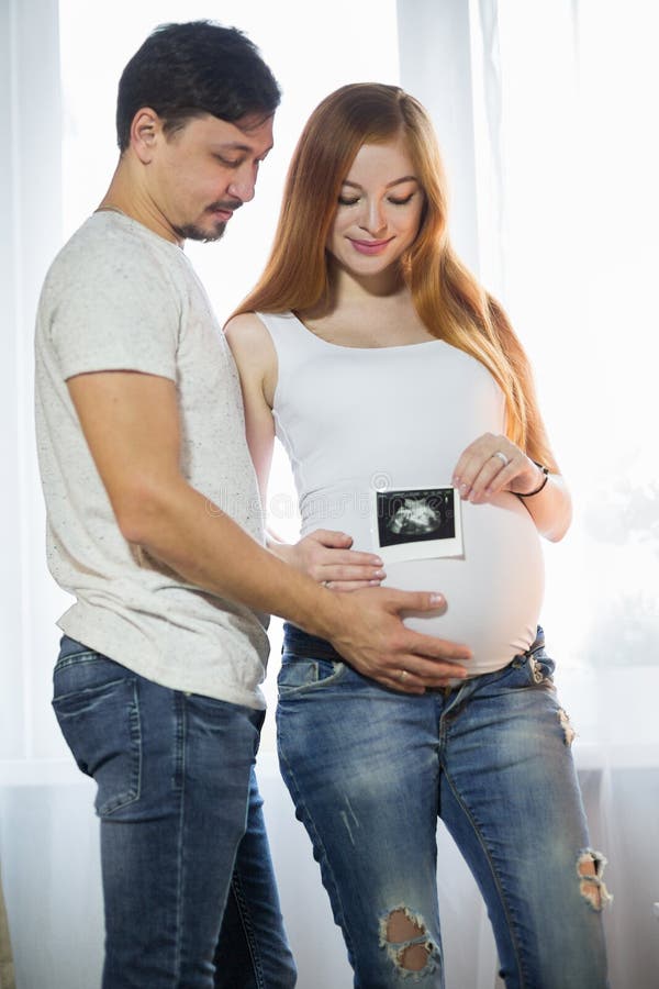 Husband and Pregnant Wife in a Room Stock Photo