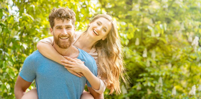 Husband trägt seine Frau auf den Rücken und ist ein verlässlicher Partner stockbild