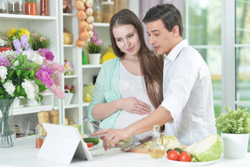 Wife cooking. Муж готовит с беременной женой. Husband and wife are in the Kitchen and husband is drinking.