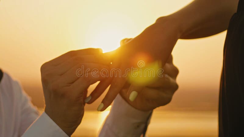 Huwelijk Ring Put On Finger Hands wat betreft van de Bruidegomman woman marriage van de Zonsondergangbruid de Wittebroodsweken va
