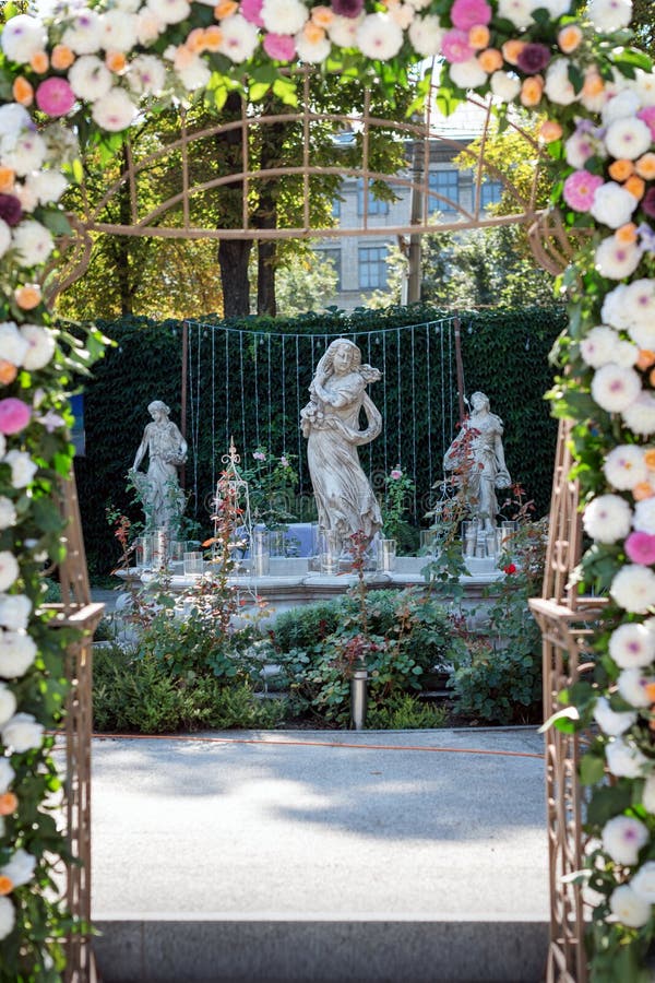 Huwelijksboog met bloemen in openlucht Mooie huwelijksopstelling Huwelijksceremonie in de tuin met beeldhouwwerken en royalty-vrije stock foto Huwelijksboog met bloemen in openlucht Mooie huwelijksopstelling Huwelijksceremonie in de tuin met beeldhouwwerken en royalty-vrije stock foto