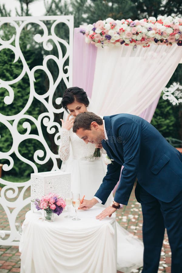 Huwelijkspaar die zich onder een boog van verse bloemen bevinden royalty-vrije stock foto's Huwelijkspaar die zich onder een boog van verse bloemen bevinden royalty-vrije stock foto's