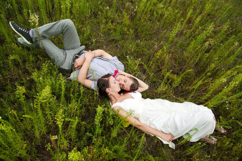 Huwelijkspaar in liefde die in groen gras in de zomerweide liggen stock foto's Huwelijkspaar in liefde die in groen gras in de zomerweide liggen stock foto's
