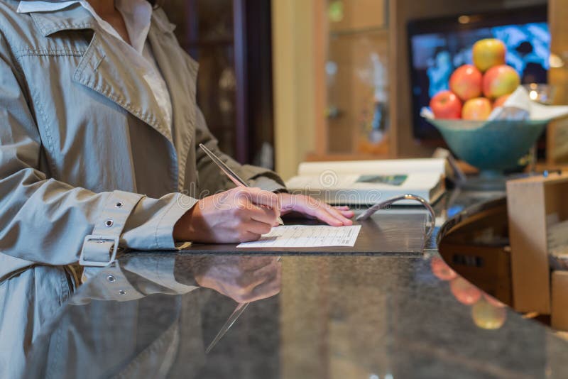 Female hotel guest filling in registration form upon checking in, service and tourism concept. Female hotel guest filling in registration form upon checking in, service and tourism concept